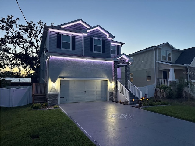view of front of home with concrete driveway, a front yard, fence, and stone siding