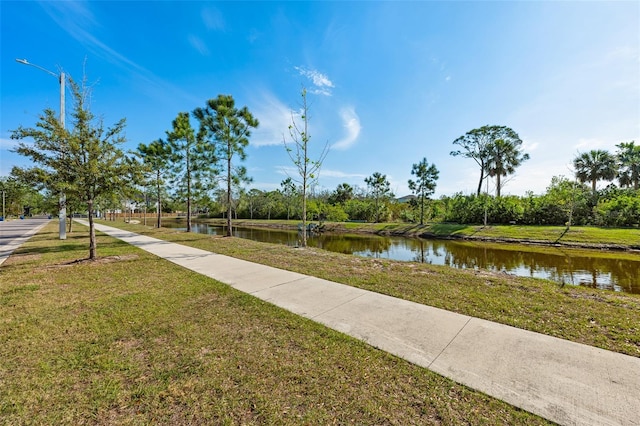 view of property's community with a lawn and a water view