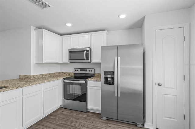 kitchen with white cabinets, visible vents, light stone countertops, stainless steel appliances, and dark wood finished floors