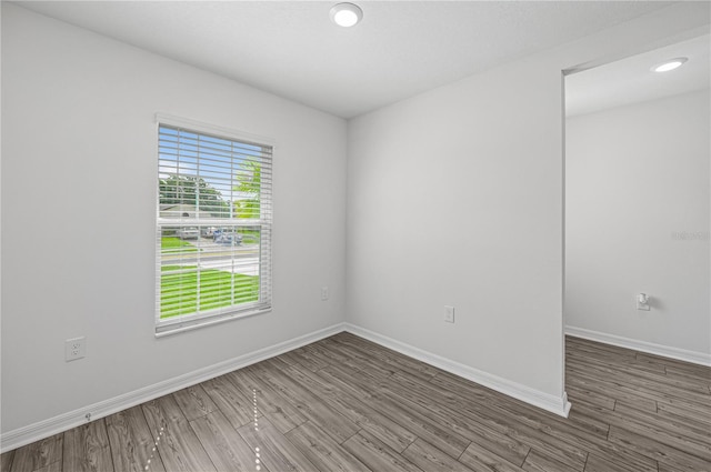 spare room with recessed lighting, baseboards, and wood finished floors