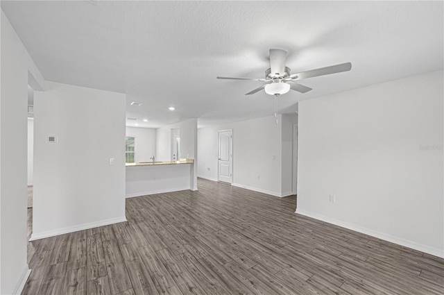 unfurnished living room with baseboards, ceiling fan, recessed lighting, a sink, and dark wood-style floors