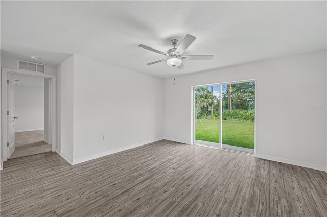 empty room featuring baseboards, visible vents, wood finished floors, and ceiling fan
