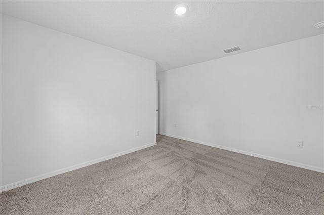 carpeted spare room with baseboards and visible vents