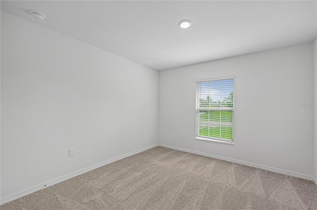 spare room featuring carpet flooring and baseboards