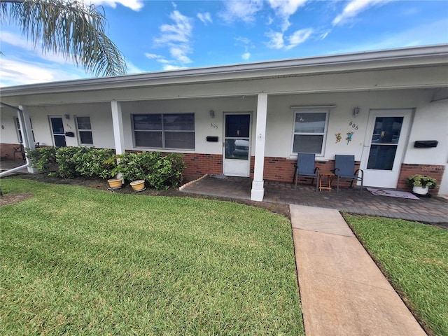 605 Brandy Wine Dr Unit 605, Largo, FL 33771 - view of front of house with stucco siding, brick siding, covered porch, and a front yard