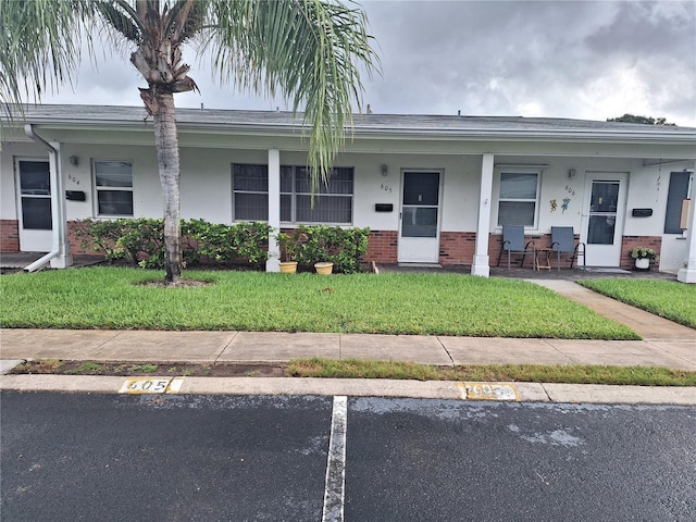 605 Brandy Wine Dr Unit 605, Largo, FL 33771 - view of front facade with stucco siding, uncovered parking, a front yard, and brick siding