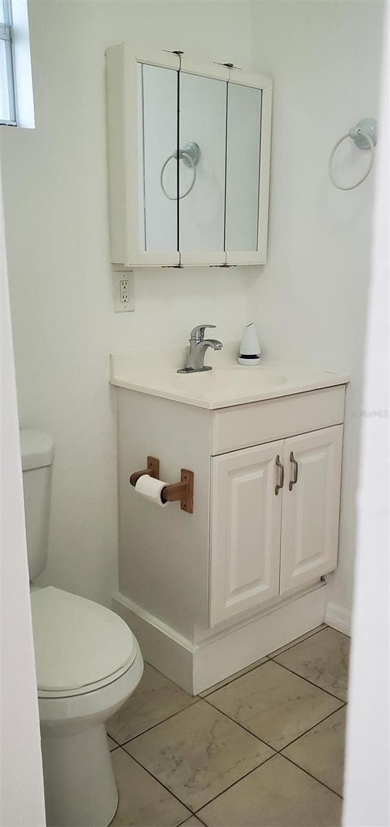 half bathroom featuring toilet, vanity, and tile patterned flooring