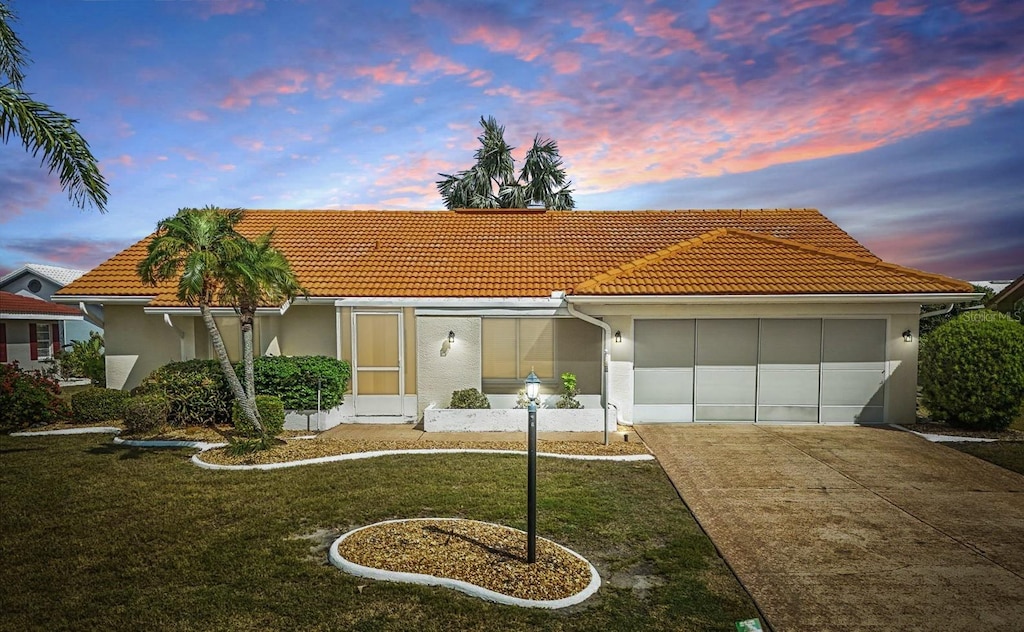 1805 Granville Ln, Sun City Center, FL 33573 - mediterranean / spanish-style home featuring concrete driveway, a tile roof, a garage, and stucco siding