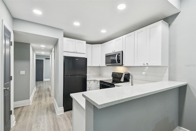 3411 N 12th St, Tampa, FL 33605 - kitchen featuring decorative backsplash, white cabinetry, black appliances, and a peninsula