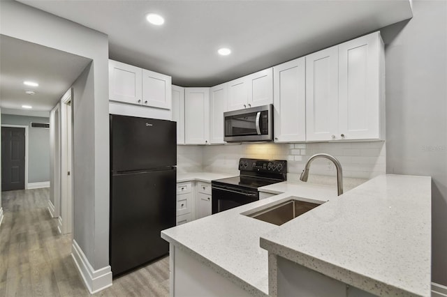 3411 N 12th St, Tampa, FL 33605 - kitchen featuring a peninsula, a sink, light stone counters, black appliances, and backsplash