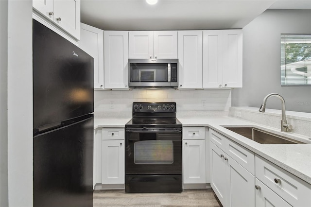 3411 N 12th St, Tampa, FL 33605 - kitchen with white cabinetry, light wood-type flooring, backsplash, a sink, and black appliances
