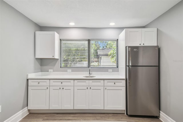 3411 N 12th St, Tampa, FL 33605 - kitchen featuring white cabinetry, light countertops, light wood-type flooring, baseboards, and freestanding refrigerator