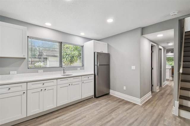 3411 N 12th St, Tampa, FL 33605 - kitchen with light countertops, white cabinets, a sink, freestanding refrigerator, and light wood-style flooring