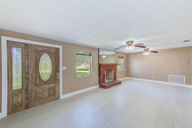 foyer featuring visible vents, ceiling fan, baseboards, and a fireplace