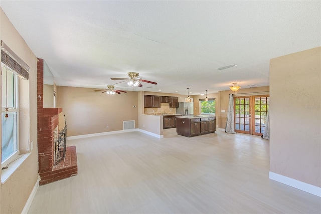 unfurnished living room featuring baseboards, ceiling fan, a fireplace, and visible vents
