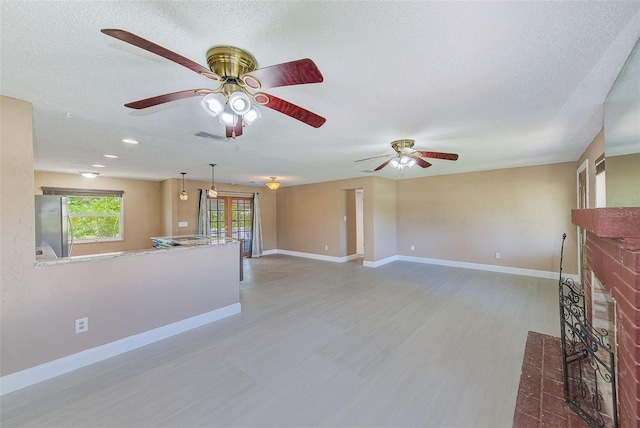 unfurnished living room with ceiling fan, wood finished floors, a brick fireplace, and baseboards