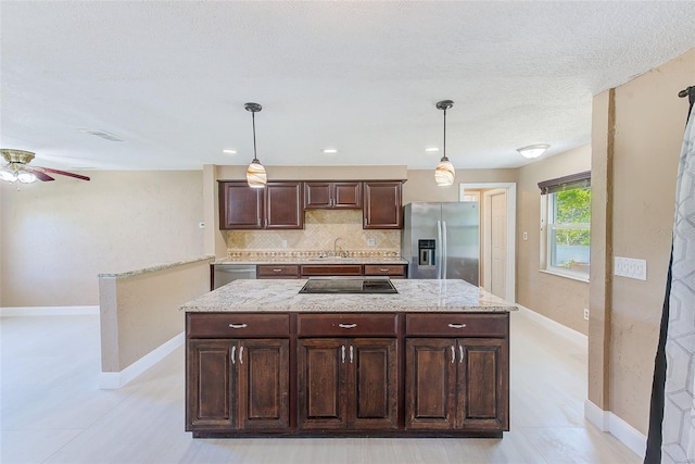 kitchen featuring ceiling fan, dark brown cabinetry, a sink, stainless steel appliances, and backsplash