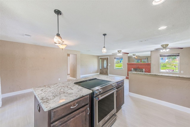 kitchen featuring a wealth of natural light, high end range, visible vents, and a ceiling fan