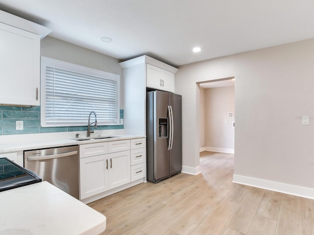 kitchen with light countertops, a sink, stainless steel appliances, and light wood finished floors