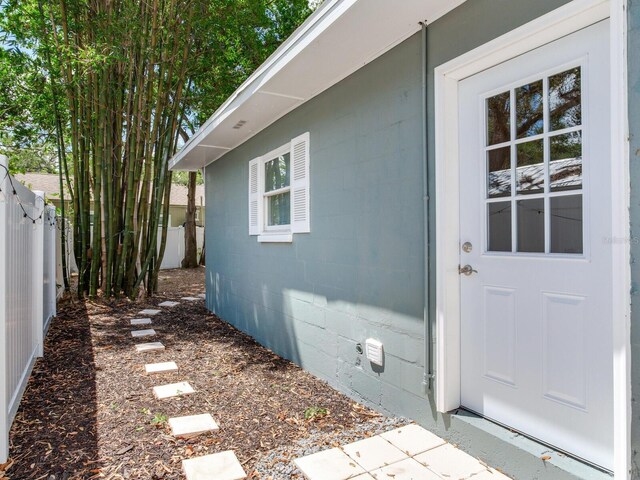 property entrance featuring concrete block siding and fence