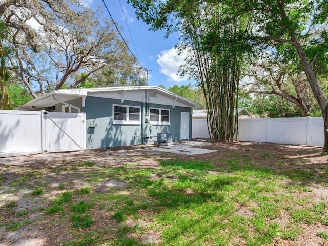 rear view of house featuring concrete block siding, a gate, and fence