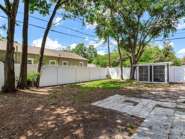 view of yard featuring a fenced backyard, a sunroom, and a patio