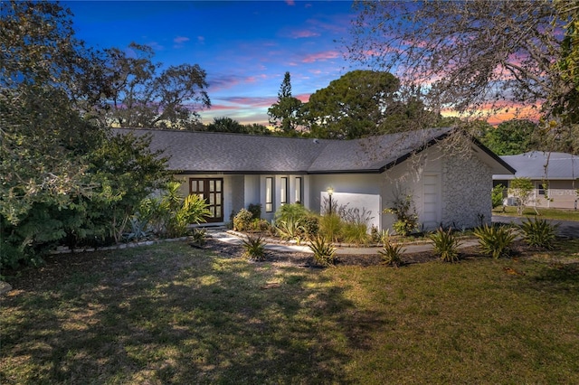 view of front of home with roof with shingles, stucco siding, and a lawn