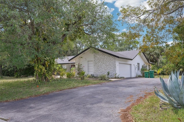 view of home's exterior featuring a garage, driveway, and stone siding