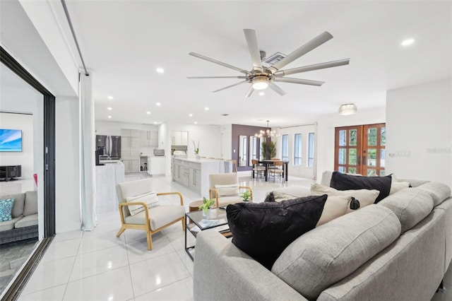 living room with recessed lighting, ceiling fan with notable chandelier, and light tile patterned flooring