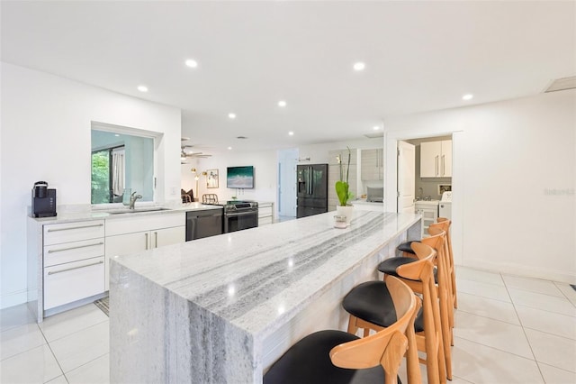 kitchen with black fridge, light tile patterned flooring, white cabinets, stainless steel range with electric cooktop, and dishwasher