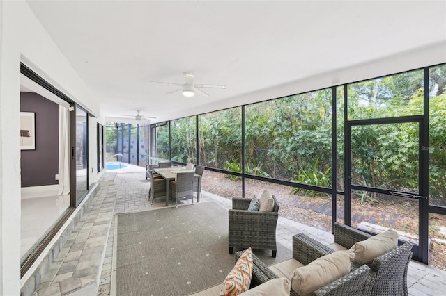 unfurnished sunroom featuring an outdoor living space, a ceiling fan, and a healthy amount of sunlight