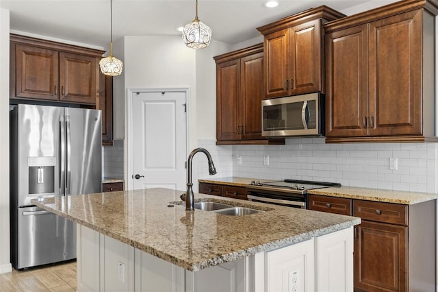 kitchen with light stone countertops, a sink, tasteful backsplash, and appliances with stainless steel finishes