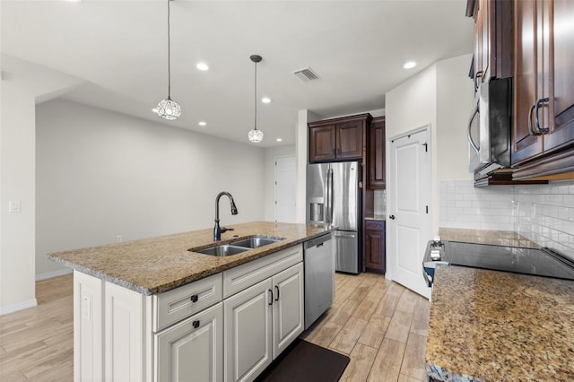kitchen with a sink, appliances with stainless steel finishes, light wood finished floors, and visible vents