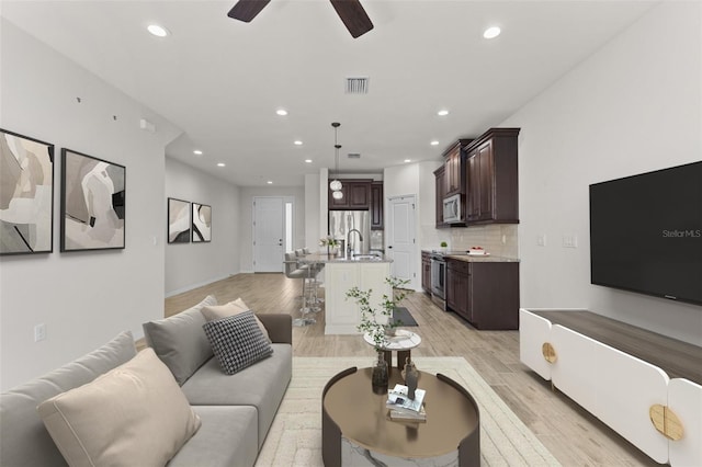 living room featuring light wood-style flooring, visible vents, recessed lighting, and ceiling fan