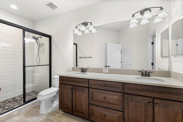 bathroom featuring visible vents, a sink, a stall shower, and toilet