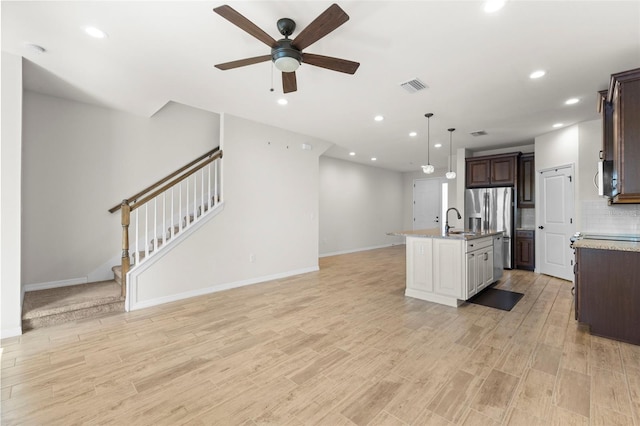 kitchen featuring visible vents, a kitchen island with sink, stainless steel appliances, a sink, and open floor plan