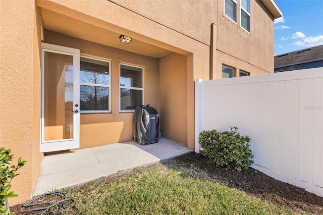 doorway to property featuring stucco siding and fence