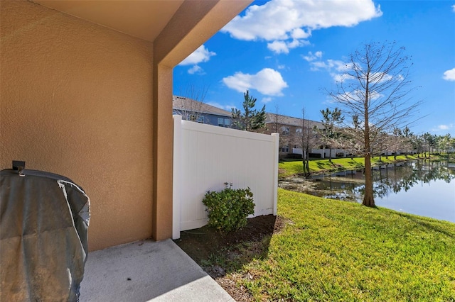 view of property exterior with stucco siding, a water view, and a lawn