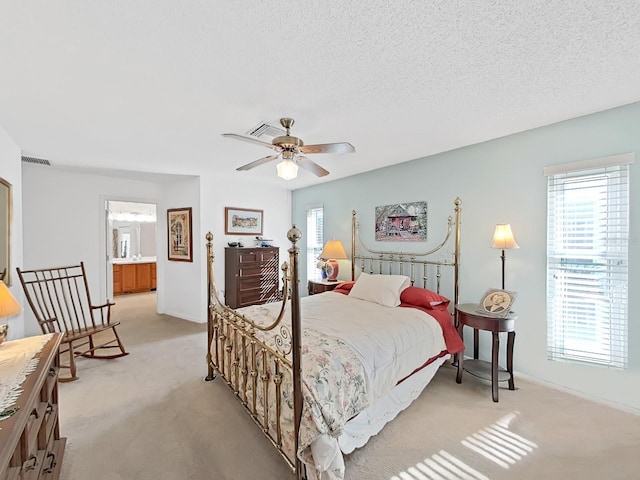 bedroom featuring a textured ceiling, light colored carpet, and visible vents