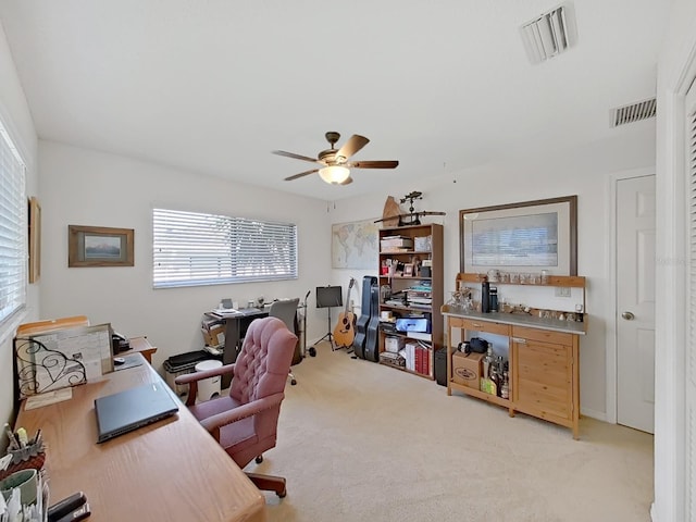 office space featuring light colored carpet, visible vents, and ceiling fan