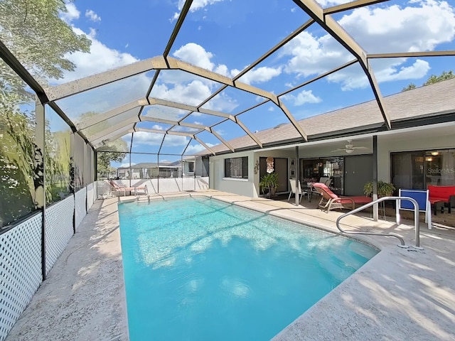 pool with glass enclosure, ceiling fan, and a patio area