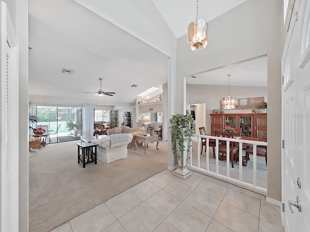 interior space with lofted ceiling, light colored carpet, light tile patterned floors, ceiling fan with notable chandelier, and visible vents