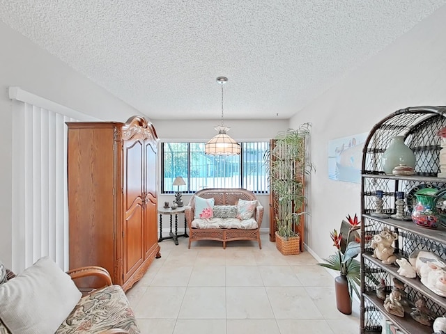 sitting room with a textured ceiling, baseboards, and light tile patterned floors