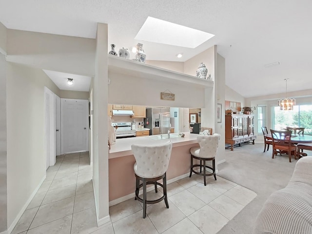 kitchen with light countertops, a peninsula, stainless steel appliances, exhaust hood, and a kitchen breakfast bar