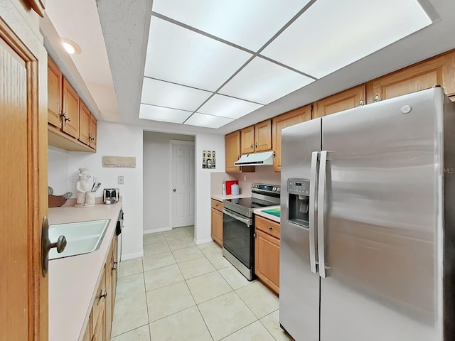 kitchen featuring light countertops, a sink, appliances with stainless steel finishes, under cabinet range hood, and light tile patterned floors