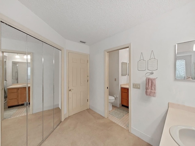 full bathroom with toilet, vanity, visible vents, and a textured ceiling