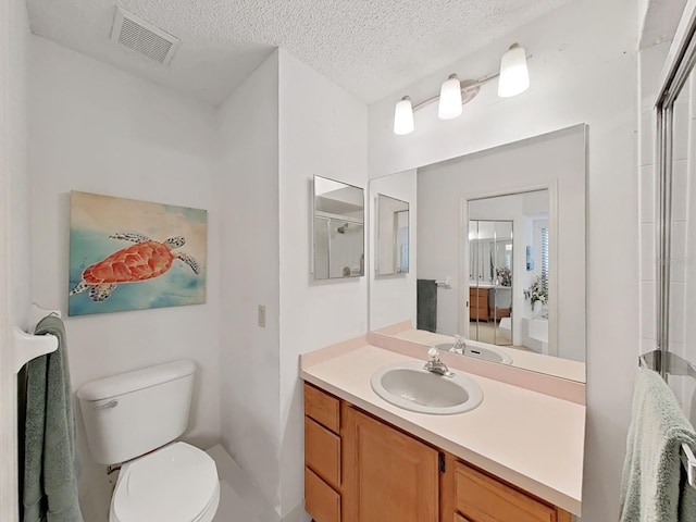 bathroom featuring a textured ceiling, visible vents, toilet, vanity, and an enclosed shower