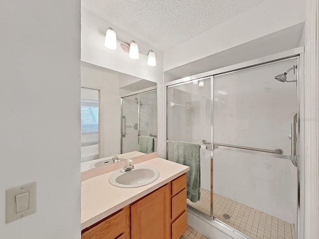 bathroom featuring vanity, a shower stall, and a textured ceiling