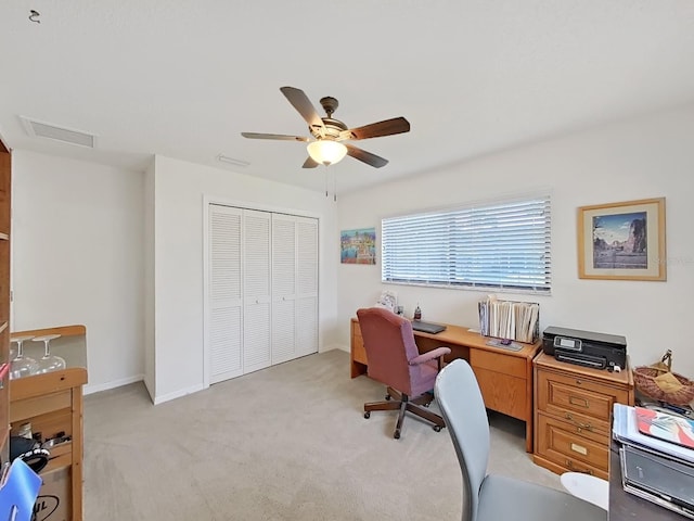 office area featuring baseboards, visible vents, a ceiling fan, and light colored carpet