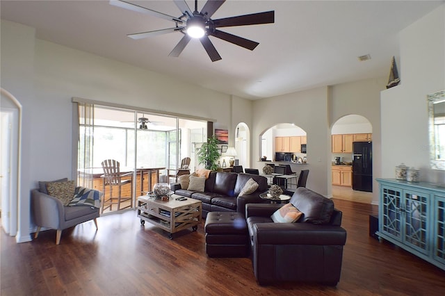 living room with arched walkways, visible vents, wood finished floors, and a ceiling fan